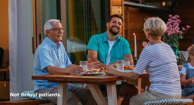 Image of three happy people sitting around a table eating together